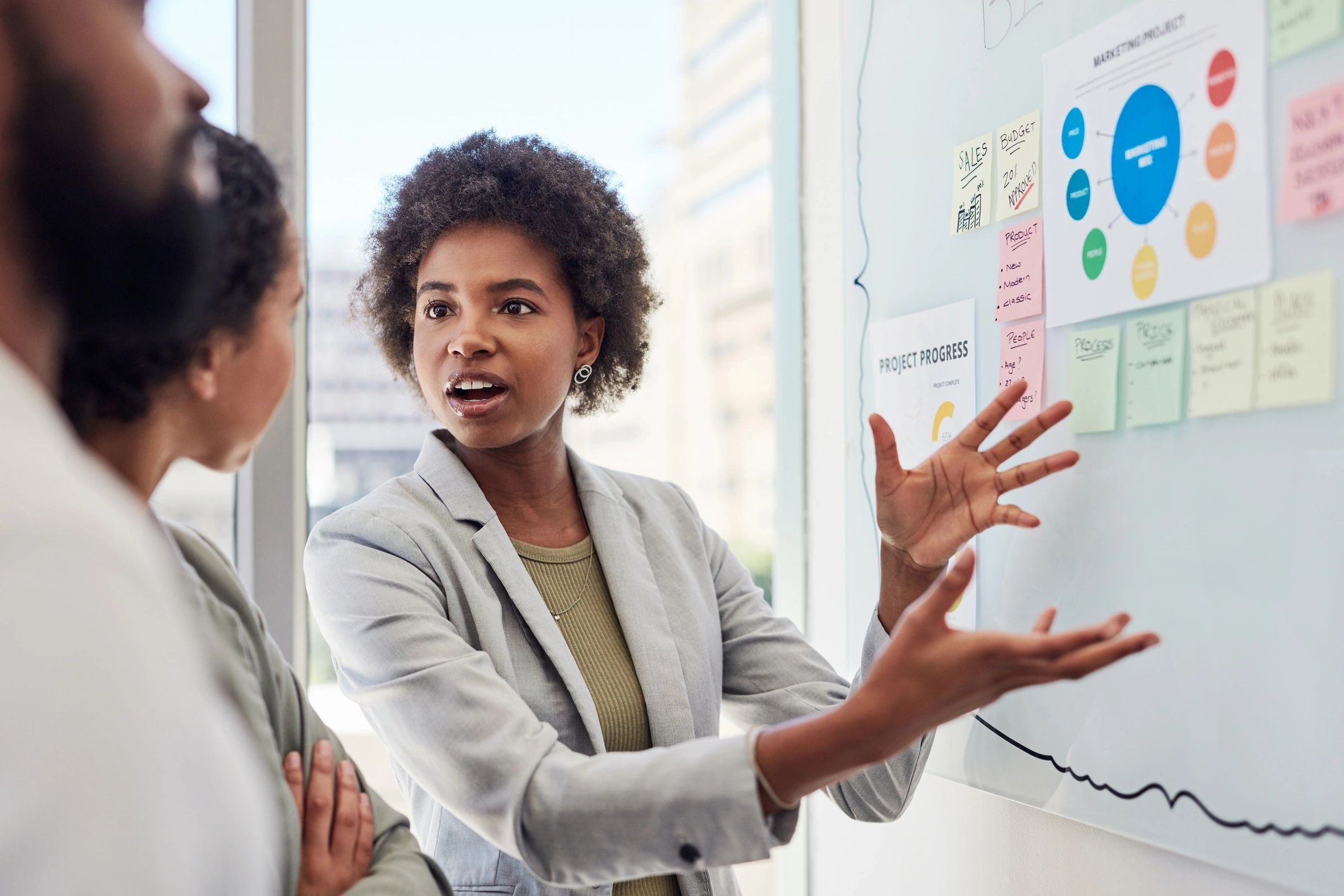 Two women are standing in front of a whiteboard.
